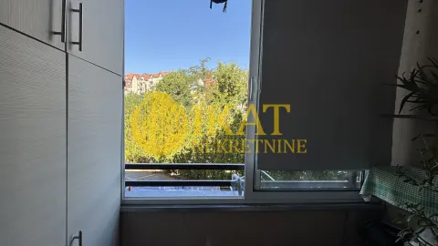 Pogled kroz prozor na zelene površine i okolne zgrade. - image 6