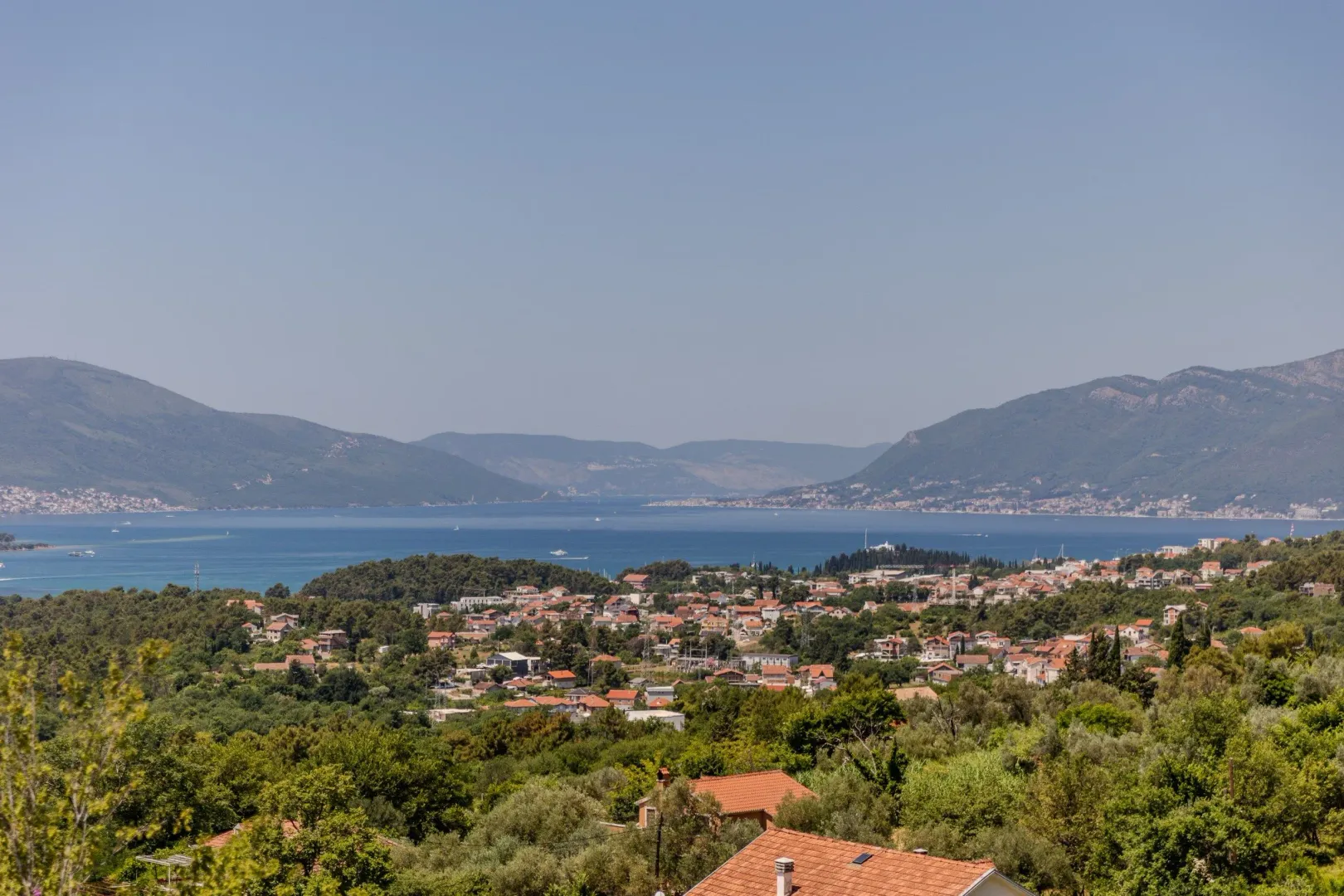 Pogled na zaliv i naselje sa zelenilom u prvom planu.