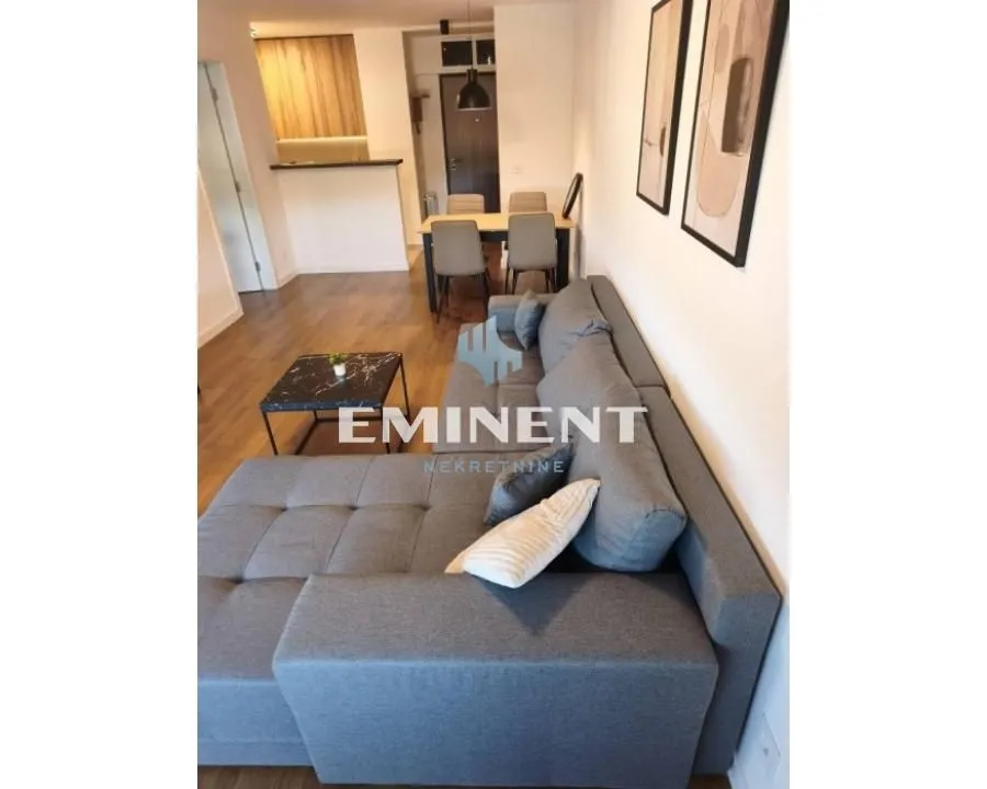 Living room with a sofa and a view towards the dining area and kitchen.