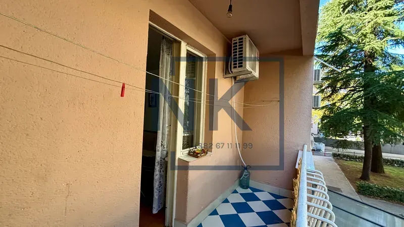 Natkriveni balkon sa pločicama u obliku šahovnice i vratima koja vode u stan.