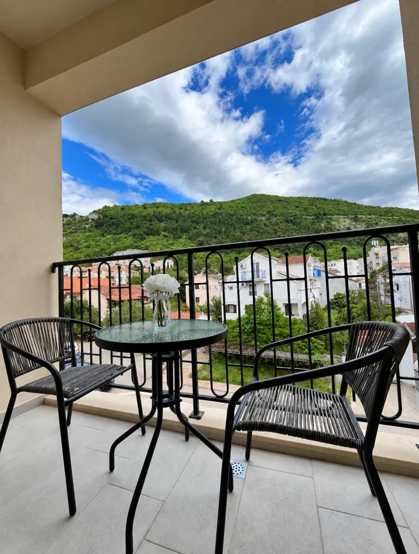 Natkriveni balkon sa garniturom za sedenje i pogledom na prirodu i okolinu.