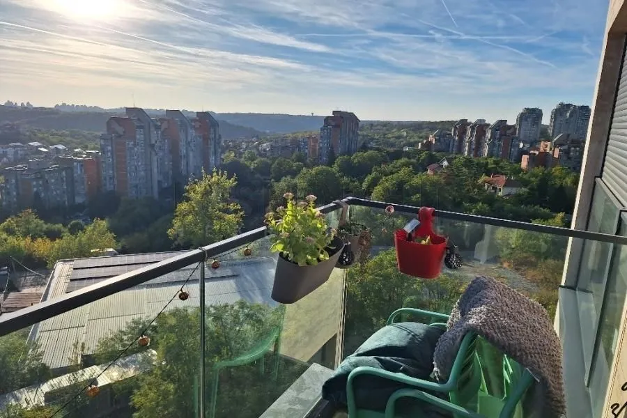 Manji namešten balkon sa pogledom na grad i zelenilo.