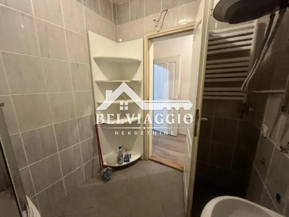 Small tiled bathroom with built-in shelves and a doorway leading to the hallway.