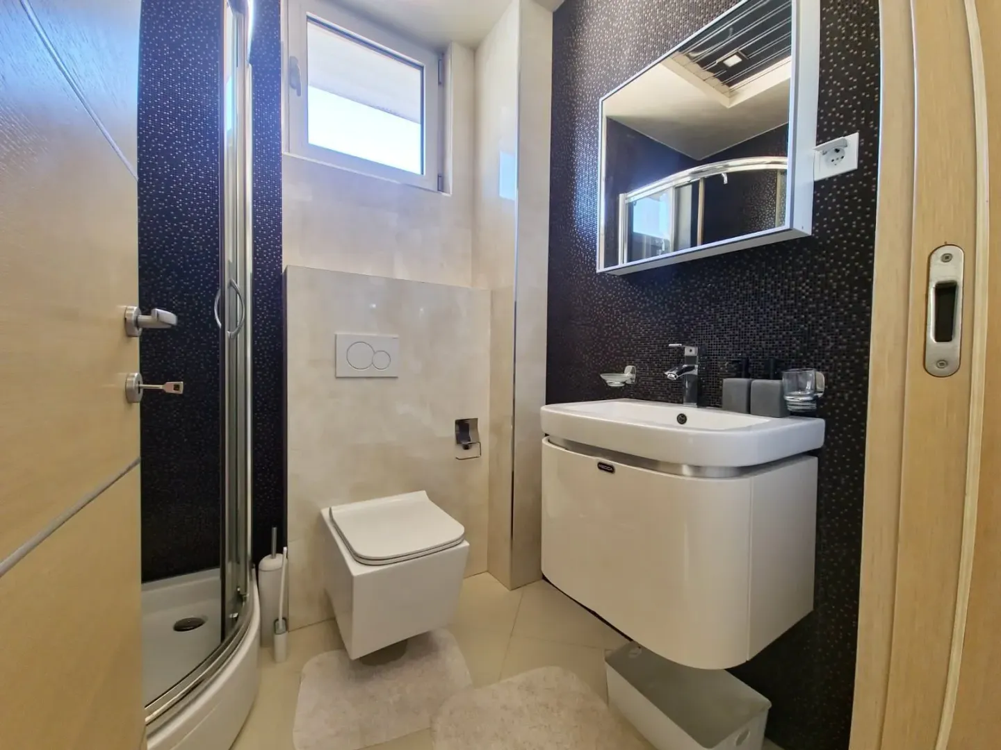 Savremeno opremljeno kupatilo sa tuš kabinom, umivaonikom i WC šoljom.
