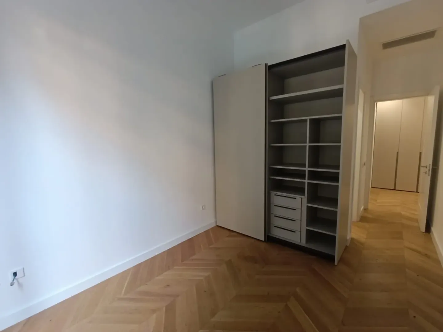 Prazna soba sa ugradnim plakarom i drvenim podom.