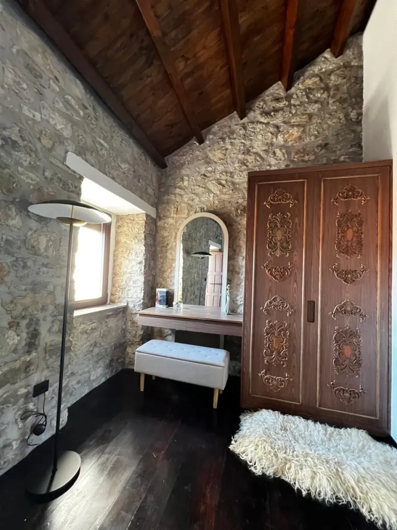 Dio spavaće sobe sa kamenim zidovima, drvenim ormarom i stolom za šminkanje.