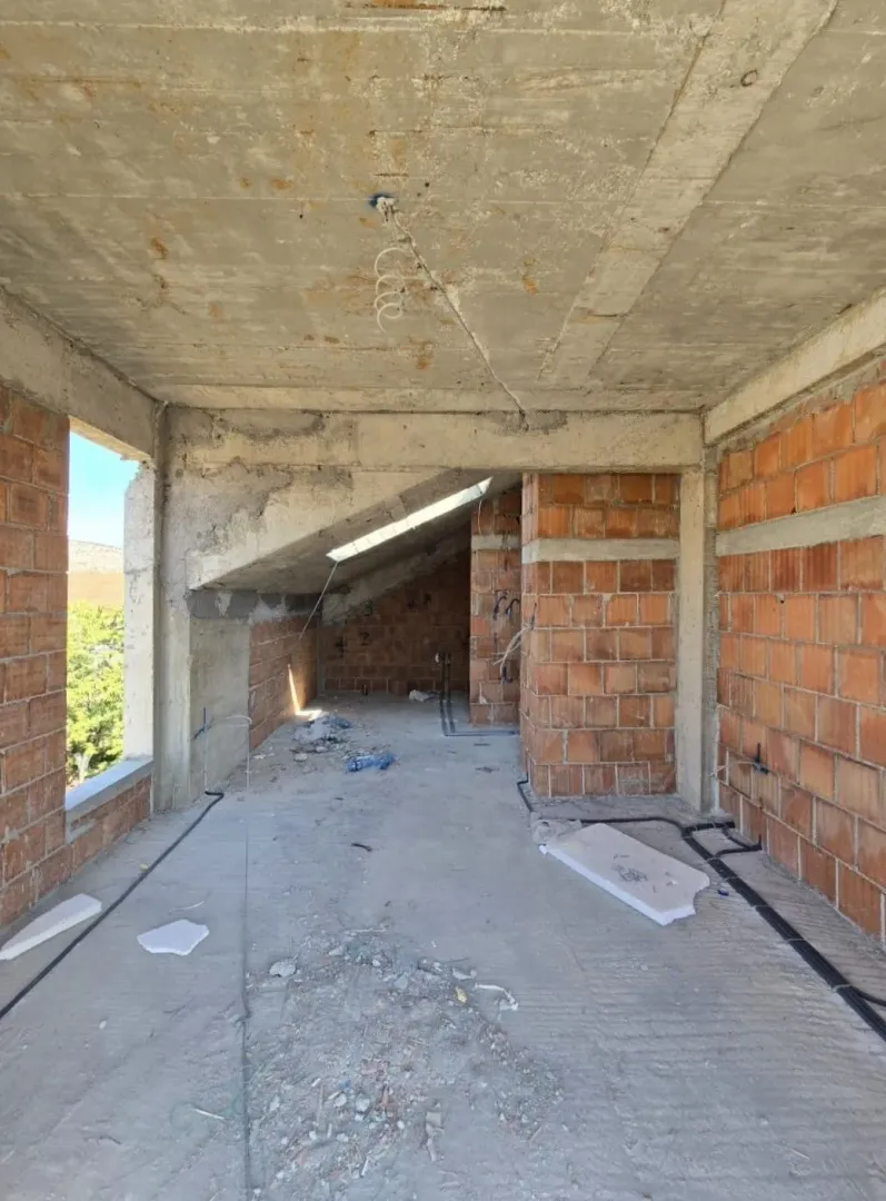 Nepotpun enterijer u izgradnji sa betonskim i ciglenim zidovima.