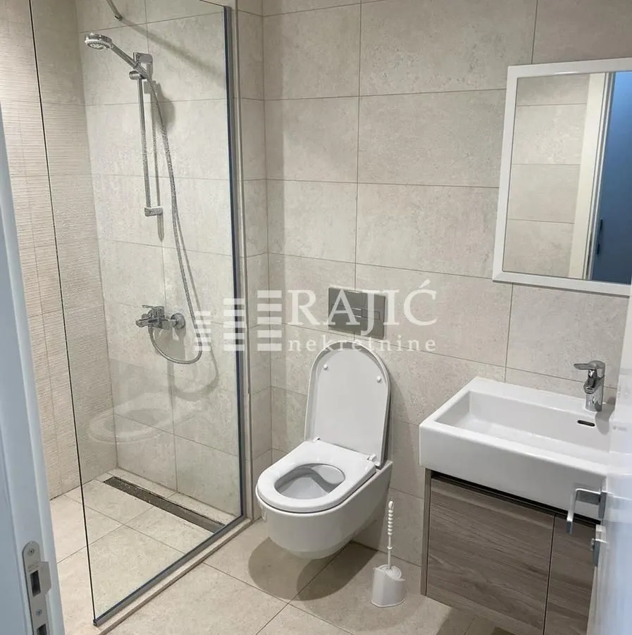 Modern bathroom with a walk-in shower, washbasin, and toilet.