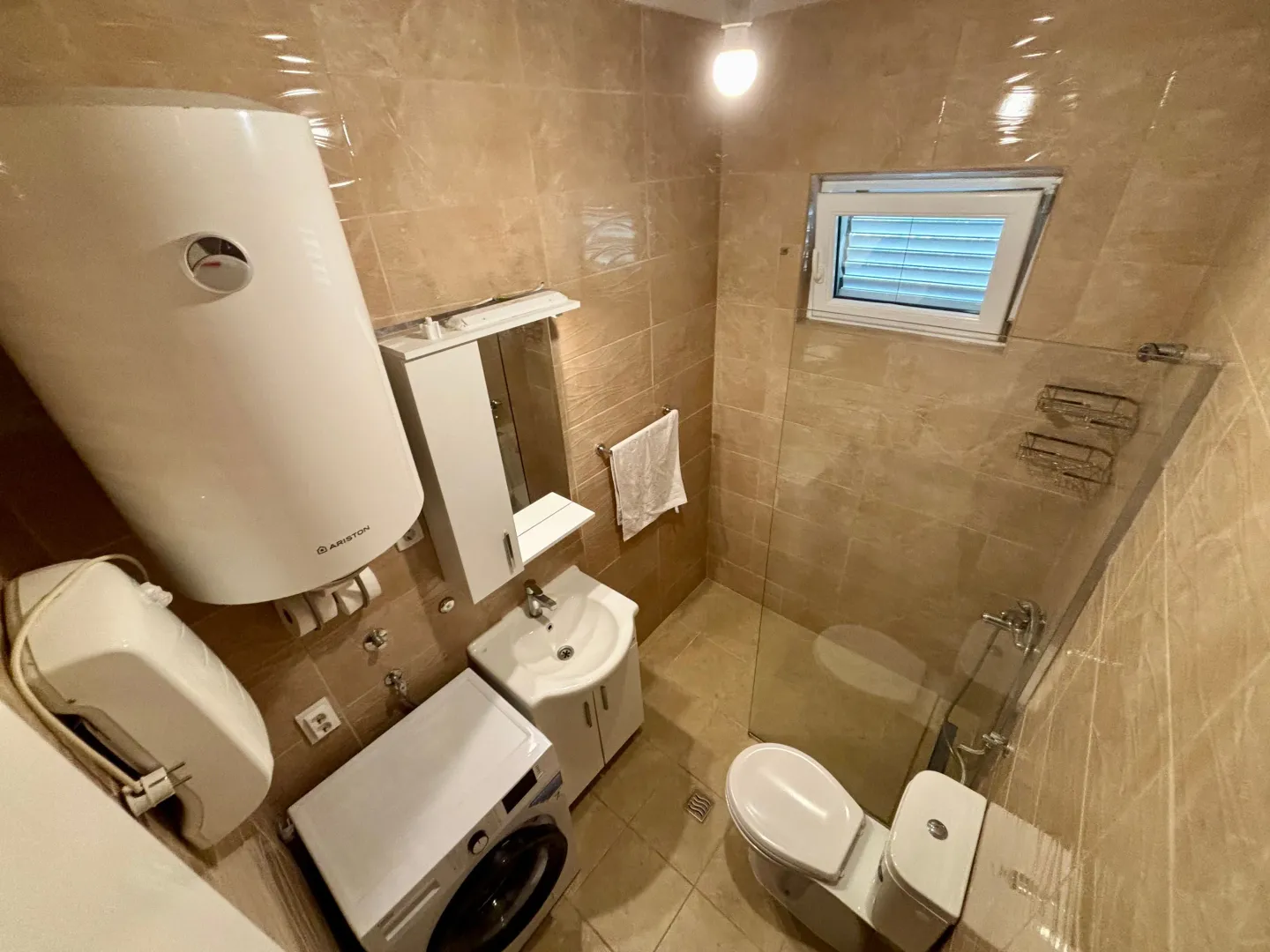 Small bathroom with a walk-in shower, washbasin, toilet, and water heater.