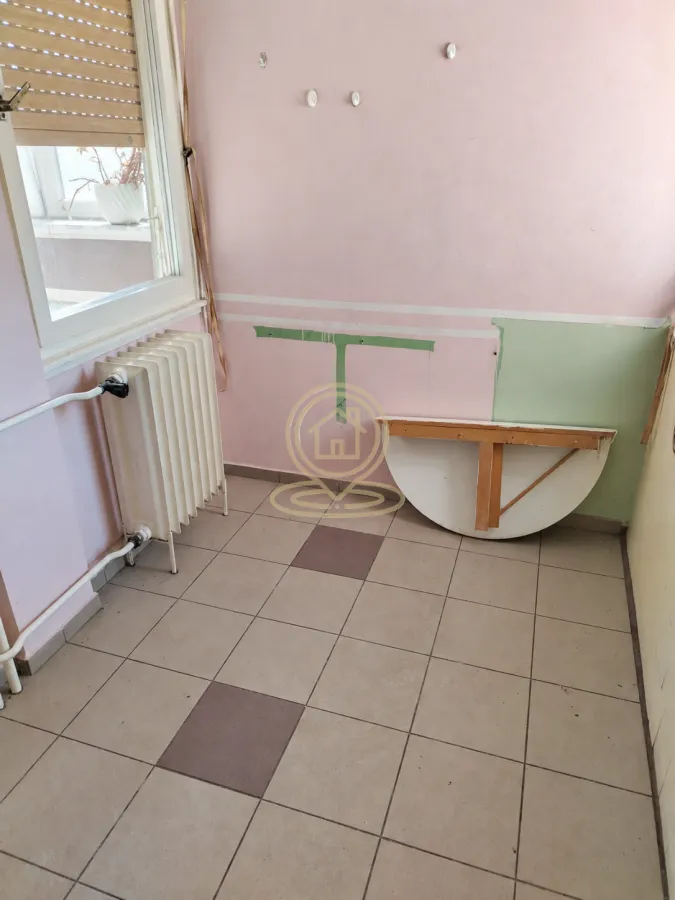 Prazna prostorija sa popločanim podom i radijatorom.