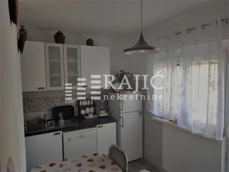 Small equipped kitchen with white units and a dining table.