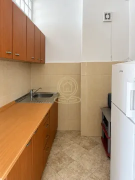 Small kitchen with wooden cabinetry, sink, and refrigerator. - image 6
