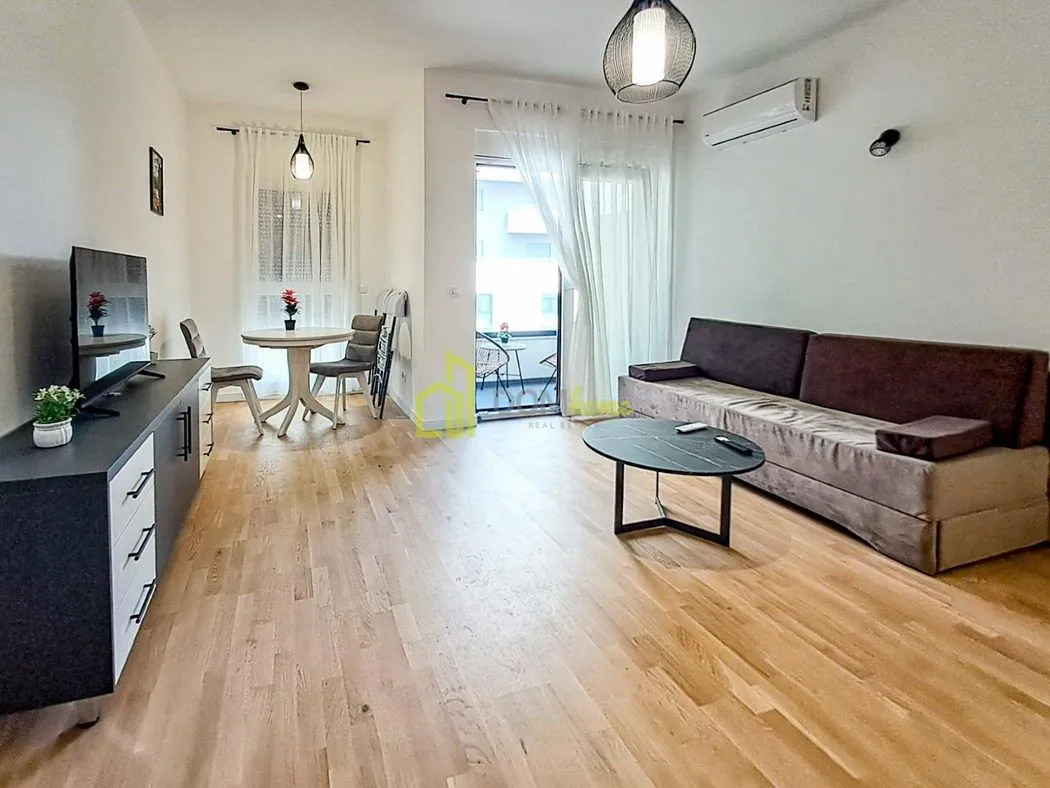 Living room with sofa, TV unit, and dining area with access to the terrace.