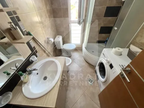 Bathroom equipped with a washbasin, shower cabin, toilet, and washing machine. - image 11