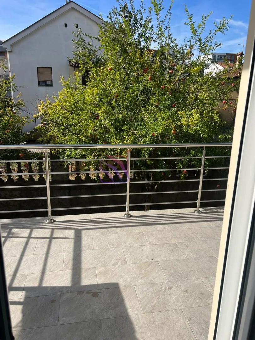 Pogled sa popločane terase na dvorište puno zelenila.