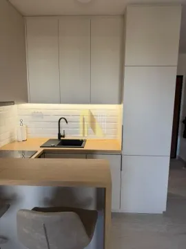 Modern kitchen with white units and a breakfast bar. - image 10