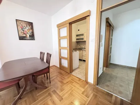 Dining area with wooden table and chairs, looking into the kitchen and hallway. - image 10
