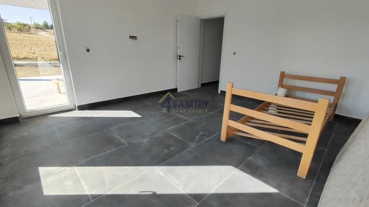 Empty room with dark floor tiles and a wooden bed frame.