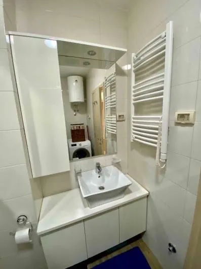 Small bathroom with a sink, mirror, and white tiles.