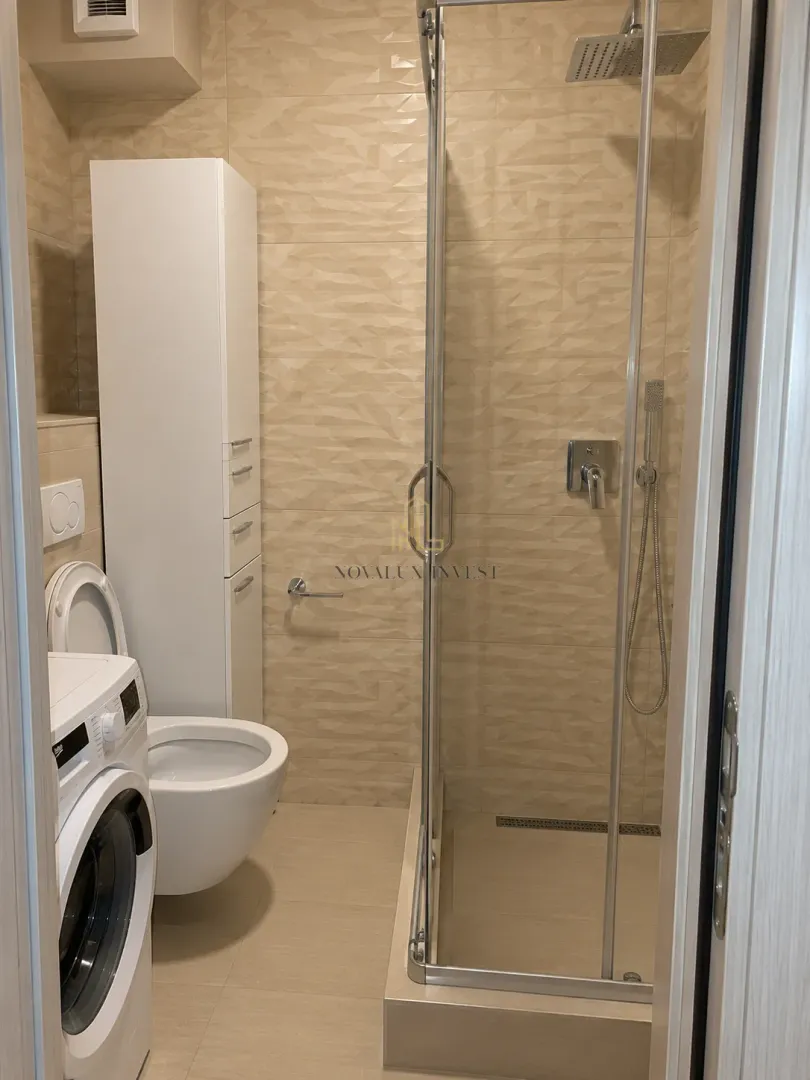 Bathroom equipped with a shower cabin, toilet, cabinet, and washing machine.