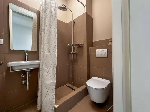 Manje kupatilo sa tuš kabinom, umivaonikom i toalet šoljom u braon tonovima. - image 11
