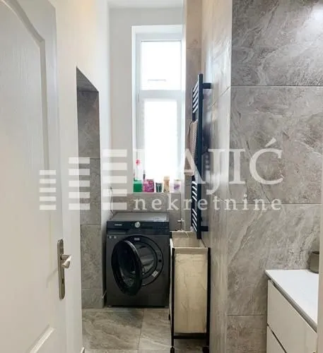 Small bathroom with a washing machine and shower.