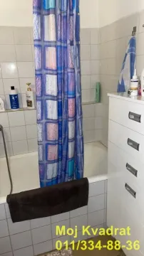 Kupatilo sa kadom, tuš zavesom i belom komodom. - image 8
