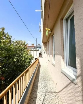Dugi balkon sa metalnom ogradom i pogledom na zeleno drveće. - image 10