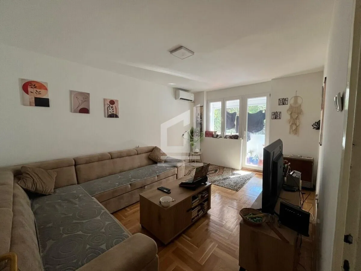 Dnevna soba sa garniturom, stočićem i televizorom.