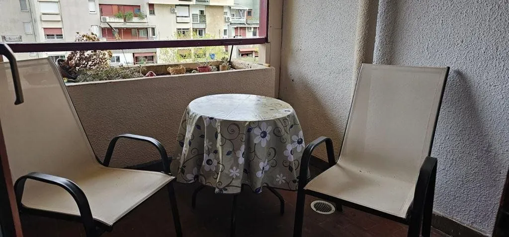Natkriveni balkon sa garniturom za sjedenje i stočićem.