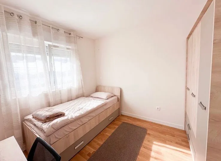 Small bedroom with a bed, wardrobe, and window.
