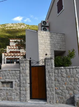 Eksterijer kuće sa kamenom ogradom i dvorišnim ulazom. - image 11