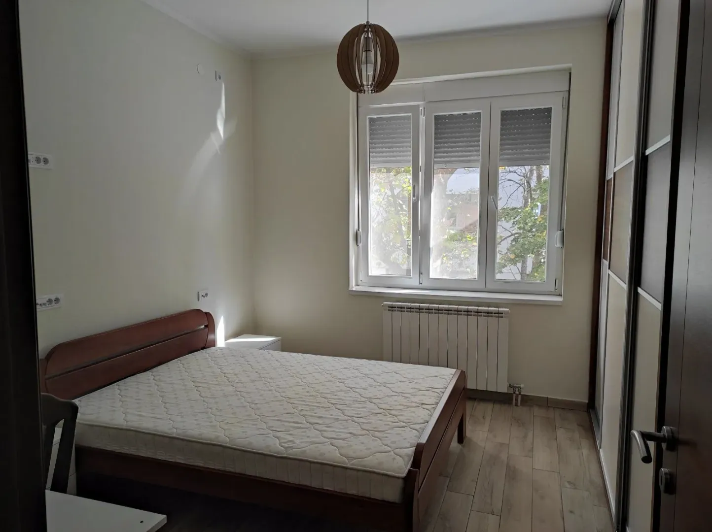 A bright bedroom featuring a wooden bed and a built-in wardrobe.
