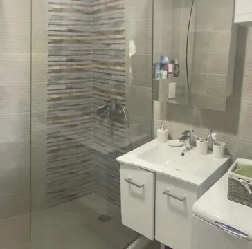 Modern equipped bathroom with a walk-in shower and sink cabinet. - image 6