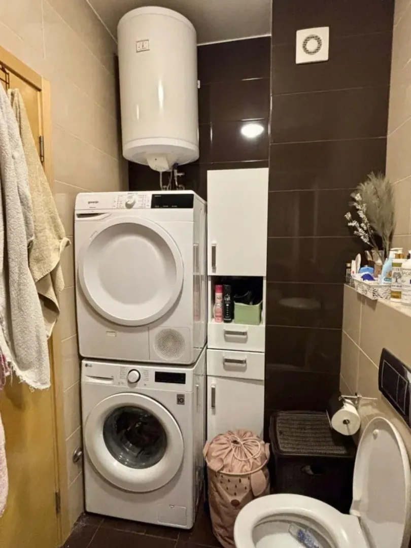 Small bathroom with a washing machine, water heater, and toilet.