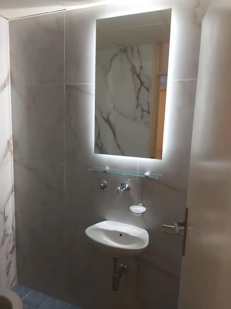 Pogled na umivaonik sa ogledalom u uređenom kupatilu.