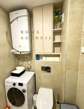 Small bathroom with a washing machine, water heater, and built-in units. - image 6