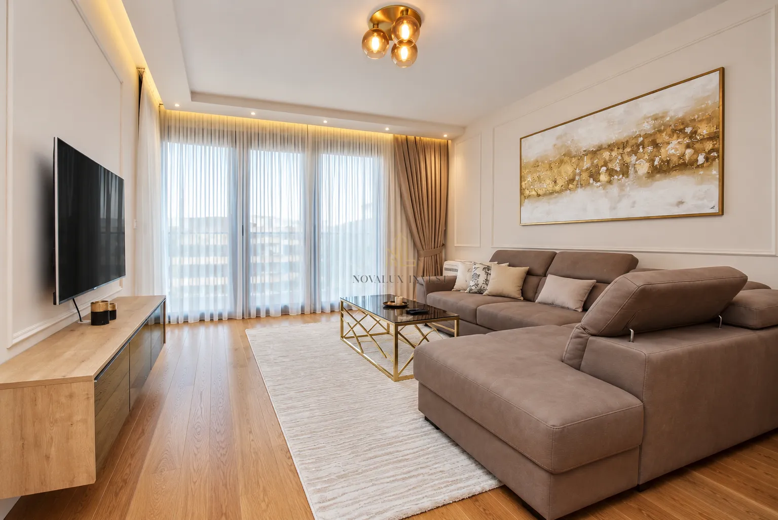 Living room with a sectional sofa, TV, and a large window with curtains.