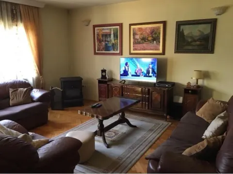 Dnevna soba sa kožnom garniturom, drvenim klub stolom i televizorom. - image 4