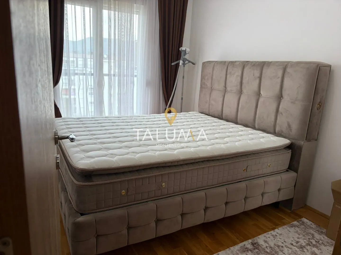 Furnished bedroom with a double bed and a window with curtains.