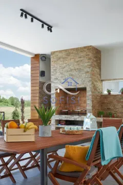 Covered terrace with a wooden table, chairs, and a built-in barbecue. - image 18