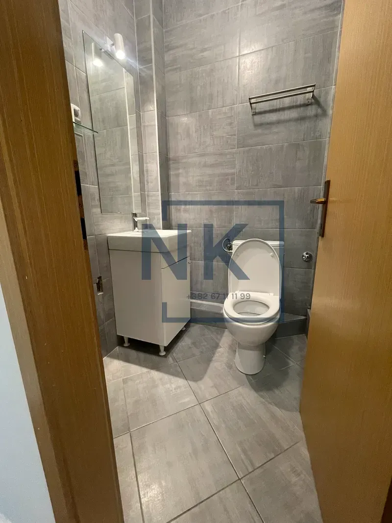 Smaller bathroom with grey tiles, vanity sink and toilet.