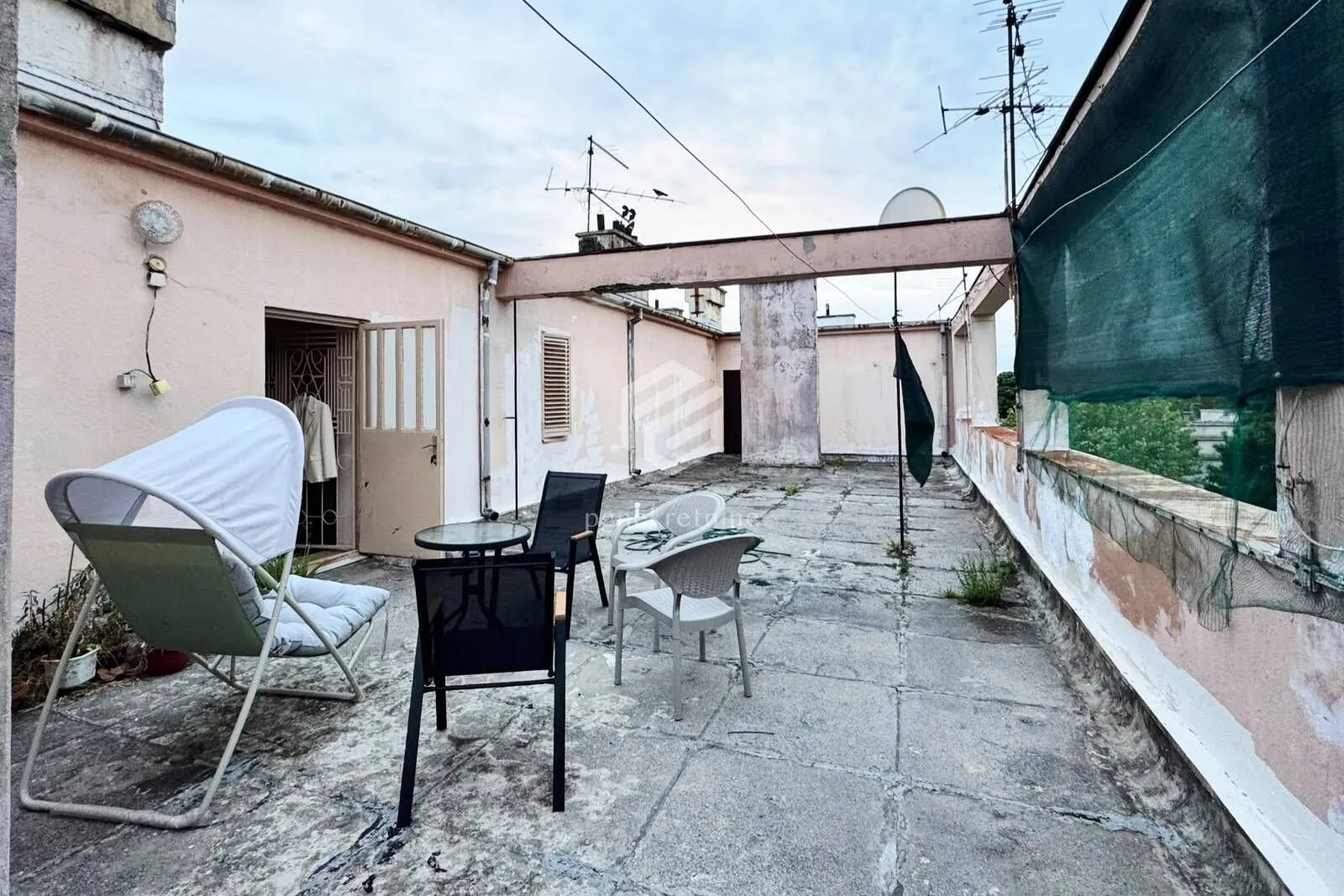 Velika prostrana terasa sa garniturom za sjedenje i pogledom na krovove.