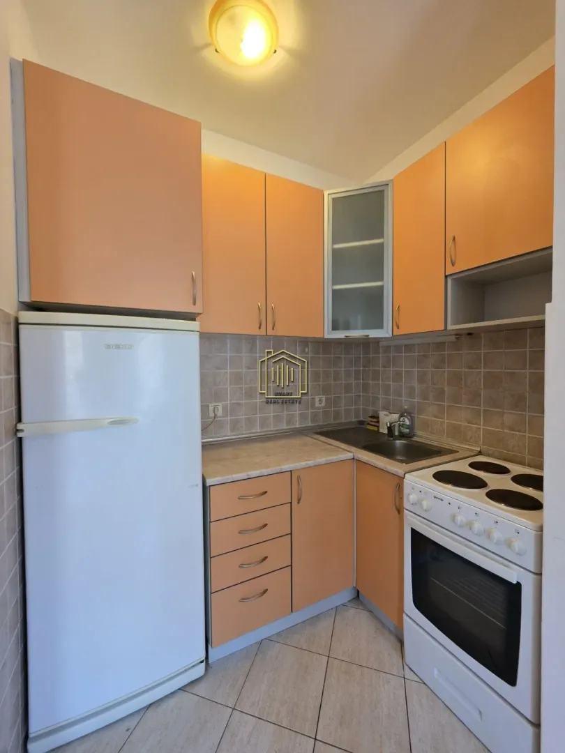Small kitchen with orange cabinets and a refrigerator.