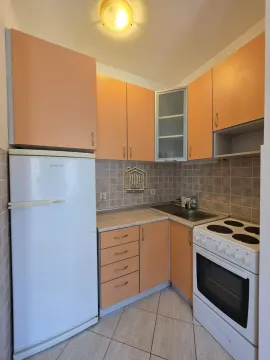 Small kitchen with orange cabinets and a refrigerator. - image 4