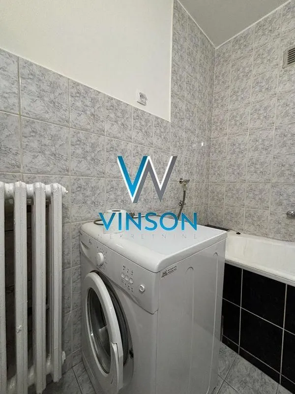 Kupatilo sa kadom, veš mašinom i keramičkim pločicama.
