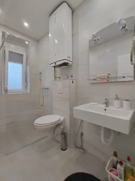 Modern bathroom equipped with a shower cabin, washbasin, and water heater. - image 9