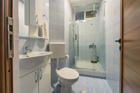 Small bathroom with a sink, toilet, and shower cabin tiled throughout. - image 9