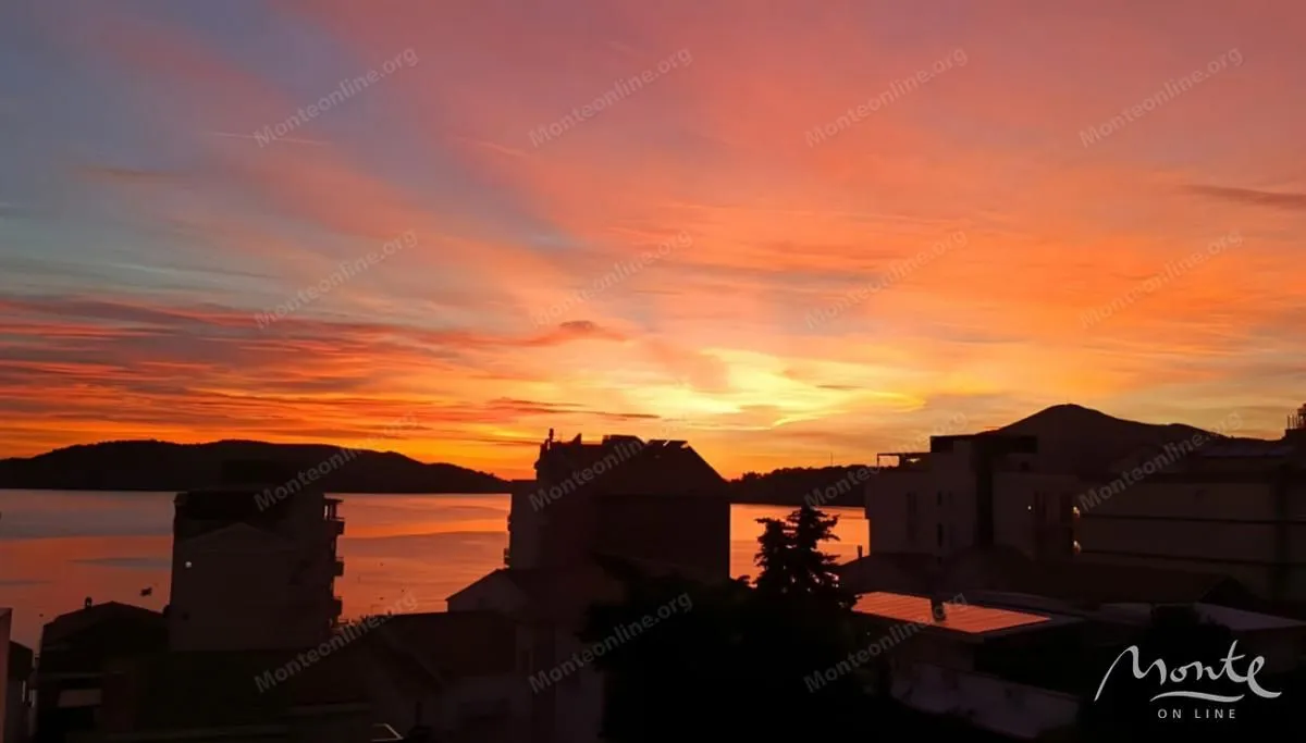 Pogled na zalazak sunca iznad mora i gradskog pejzaža.