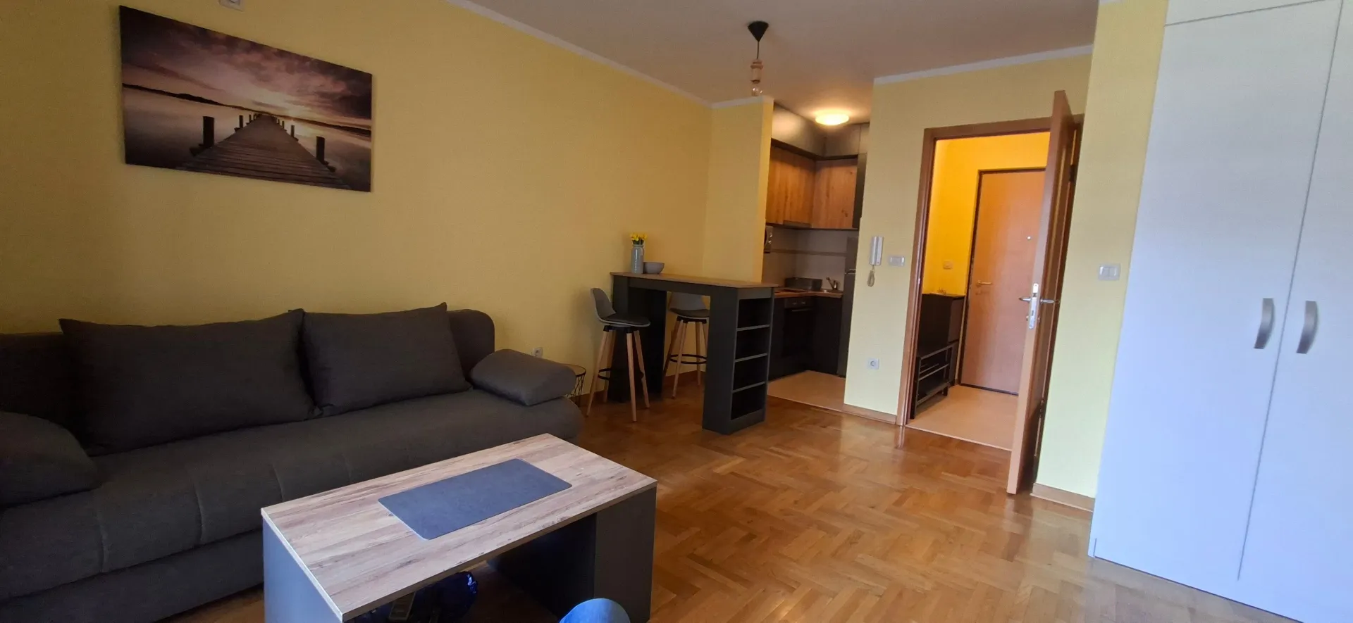 Living room with a sofa, coffee table, and a view of the kitchen.